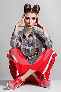 A picture of a fun, positive model wearing a plaid shirt, red sweatpants and sneakers. Studio photo session