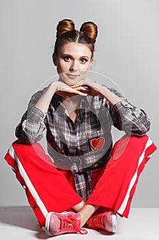 A picture of a fun, positive model wearing a plaid shirt, red sweatpants and sneakers. Studio photo session