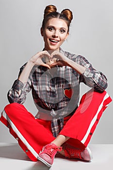 A picture of a fun, positive model wearing a plaid shirt, red sweatpants and sneakers. Studio photo session