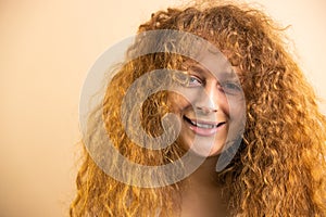 Picture of a funny joyful redhead pretty smiling woman looking at the camera over a golden background, copy space.