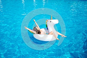 A picture of girl swimming in pool alone. She lies on air mattress and poses. Girl os resting. She has some fun.