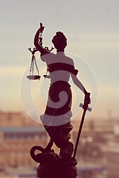 Picture of goddess Themis or Lady Justice standing on window holding sword blindfold on the city outdoors background