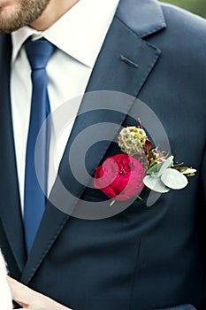 Picture of groom with blue tie and red rose boutonniere on wedding day