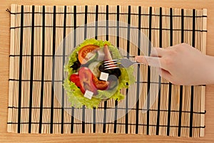 Picture of hand with fork with greek salad