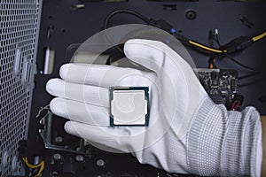 Picture of a hand wearing white gloves with a CPU chip placed on it