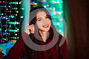 Picture of happy cheerful beautiful girl whit pretty white smile in studio with Christmas lights. Pretty smiling girl on colorful