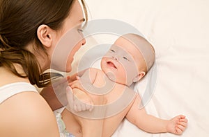 Picture of happy mother with adorable baby lying on bed