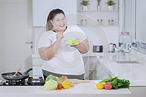 Obese woman tasting a bowl of healthy salad photo