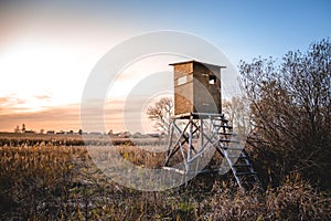 Picture of a hunting tower or a raised hide or blind on a field at dawn.