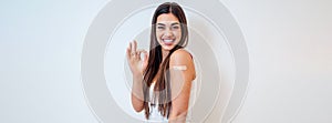 Portrait of lovely young adult woman, giving approval sign, wearing band aid