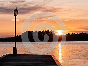 Picture of Lakeside Sunset with wooden pier and trees at the background