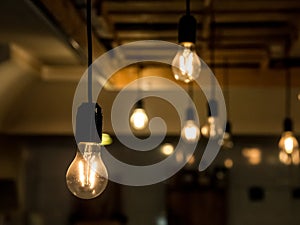 Vintage incandescence lightbulbs, with their iconic filament, hanging on the roof inside a hipsterish industrial room photo