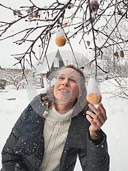 Picture of lovely middle-aged woman with frozen apple twig in winter. Rejuvenating apples. Withered skin of a rotten apple. Old