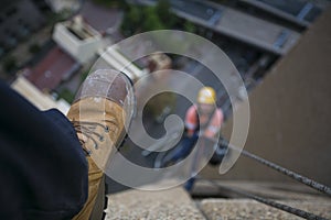 Picture of male leg setting on the edge of building site wearing blue pant, steel cape working safety boot with blurring construct