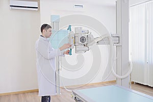 the picture of a male radiologist adjusting the X-ray machine