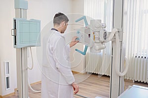 the picture of a male radiologist adjusting the X-ray machine