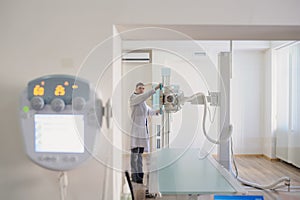 the picture of a male radiologist adjusting the X-ray machine