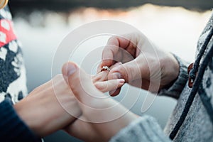 Picture of man putting engagement silver ring on woman hand, out