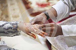 Picture of man putting wedding ring on woman hand.