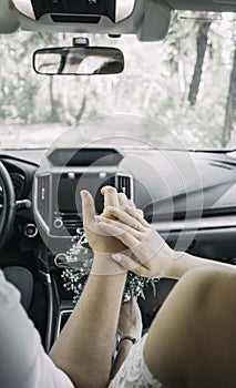 Picture of man and woman in a car. Married couple holding hands, ceremony wedding day. Newly wed couple& x27;s hands with