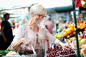 Picture of mature woman at marketplace buying vegetables