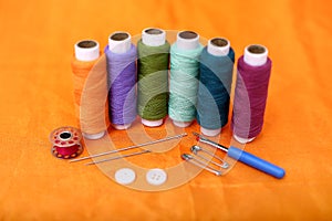 Picture of multicolored sewing thread, needle, bobbin, button, safety pin and needle ripper