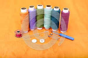 Picture of multicolored sewing thread, needle, bobbin, button, safety pin and needle ripper