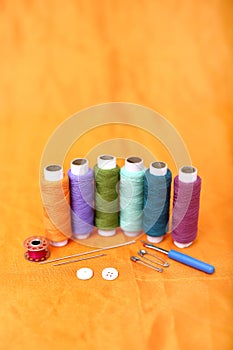 Picture of multicolored sewing thread, needle, bobbin, button, safety pin and needle ripper