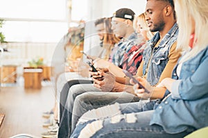 Picture of multiracial group of young people sitting with smartphones in their hands