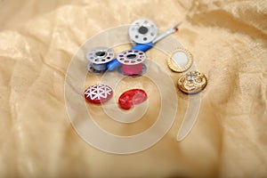 Picture of needle ripper, button and bobbin on the golden cloth
