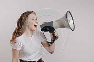 Picture of nice young woman in a white t-shurt screaming into megaphone in her left hand.