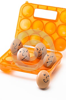 Picture of Obsolete Orange Egg Hiolder. Placed With Eggs Symbolizing Embittered Human Faces.Against White Background