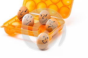 Picture of Obsolete Orange Egg Hiolder. Placed With Eggs Symbolizing Embittered Human Faces.Against White Background