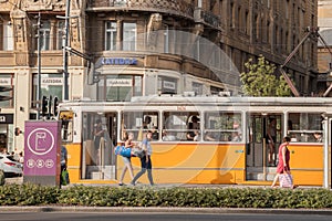Young and old people boarding a tram in the city center of Budapest, Hungarian capital city.