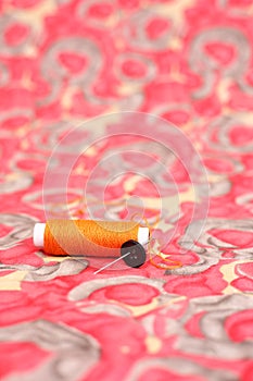 Picture of orange sewing thread, needle and button
