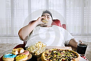 Overeating fat man sitting on the sofa