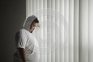 Overweight man looks lonely near the window photo