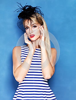 Picture perfect. A beautiful blonde woman isolated on a blue background with bright red lips.