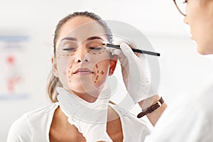 Plastic surgeon making marks on patient`s body photo