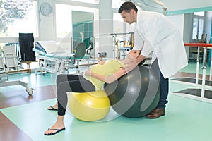 picture pregnant woman exercising with ball helped by physiotherapist