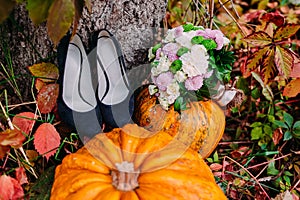 A picture of pumpkins and wedding bouquet lying near bridal shoes. Wedding decoration
