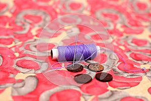 Picture of purple sewing thread, needle and four button