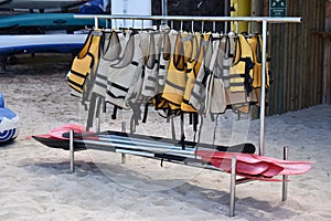 Picture of a rack of life jackets with paddles to ensure safety during the marine activities like surf, kayak, stand up paddle