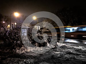 Picture of a road covered in snow and trees with a yellow motion-blurred bus on  the background