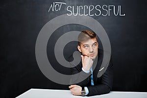 Picture of sad, concetrated man over black board with text