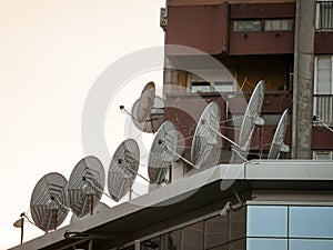 Satellite dishes and antennas on display at the top of a business building at sunset. These are used for communications