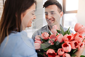 Picture showing man giving flowers to a woman at home. Romantic concept. Woman`s day photo