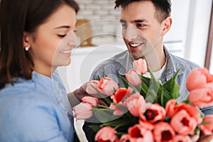 Picture showing man giving flowers to a woman at home. Romantic concept. Woman`s day photo