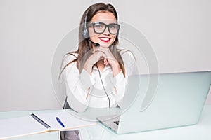 Picture of smiling female helpline operator with headphones in office