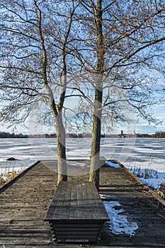 Picture of snowy wooden pier with bench and frozen trees